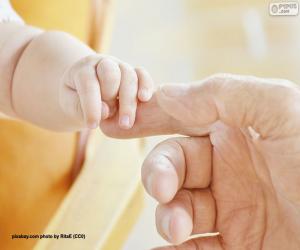 Baby picking up his father's finger puzzle