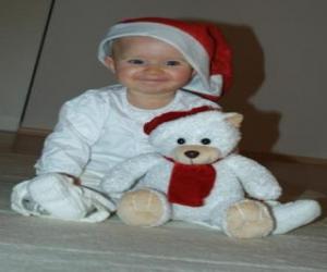 Boy with a Santa Claus hat with his teddy bear puzzle