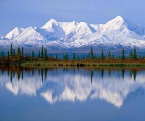 Large lake with the fir trees of the forest and mountains as a backdrop puzzle