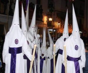 Nazarenes or penitents in a procession during Holy Week with hood or cone, robe and cape puzzle