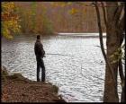 Fishing - Fisherman in river action in a forested landscape