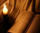 The Bible and a lit candle on the altar 