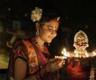 Woman kneeling with an oil lamp in hers hand in the celebration of Diwali