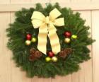 Christmas crown made of sheets of spruce, pine cones and spheres with a large color yellow ribbon