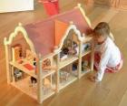 Girl playing with a doll and a doll house with furniture