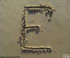 Letter "E" in capital letter written in the sand of the beach