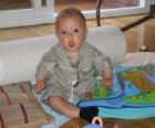 Baby, happy and content, sitting on the floor playing with a book