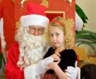 Girl talking to Santa Claus sitting on his lap