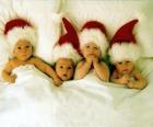 Four babies with Santa Claus hat