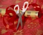 Tools to wrap holiday gifts: scissors, paper and ribbon for the tie