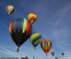 Several hot air balloons in the air, with colorful designs