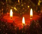Three Christmas candles with burning wick