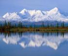 Large lake with the fir trees of the forest and mountains as a backdrop