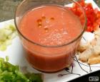 Glass of gazpacho accompanied by vegetables and bread