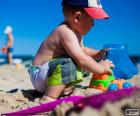 A toddler playing with a truck on the beach