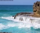 The waves break with force against the rocks of the coast