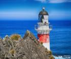 The lighthouse of Cape Palliser, with their large red stripes is a landmark for ships that sail through the Cook Strait, New Zealand