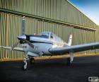 White small plane of a single propeller next to the hangar