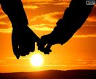 A couple in love hand in hand, observed a beautiful sunset