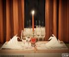 Image of a table prepared for a romantic evening, with a lighted red candle