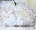 Two white hearts in front of several flowers of white peonies