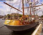 A beautiful wooden sailboat docked at the port