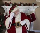 Santa Claus sitting in front of a fireplace decorated for the Christmas holidays