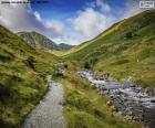 High mountain landscape with a path that follows the course of a stream