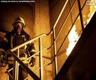 A brave firefighter during a rescue service where the access ladder is on fire