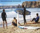 Four young surfers watching the sea from the beach