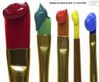 Colored brushes with paint on their top, red, green, orange, yellow and blue