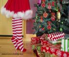 Many gifts next to an ornate Christmas tree and a girl making the last touches