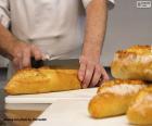 Image of a baker slicing one of his crispy loaves of bread